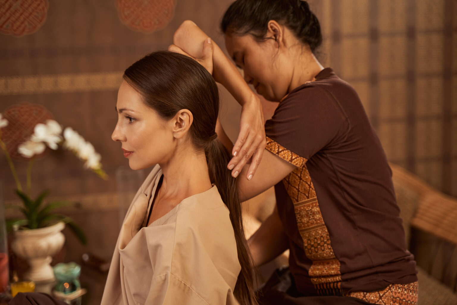 Pensive young client receiving thai stretching mas